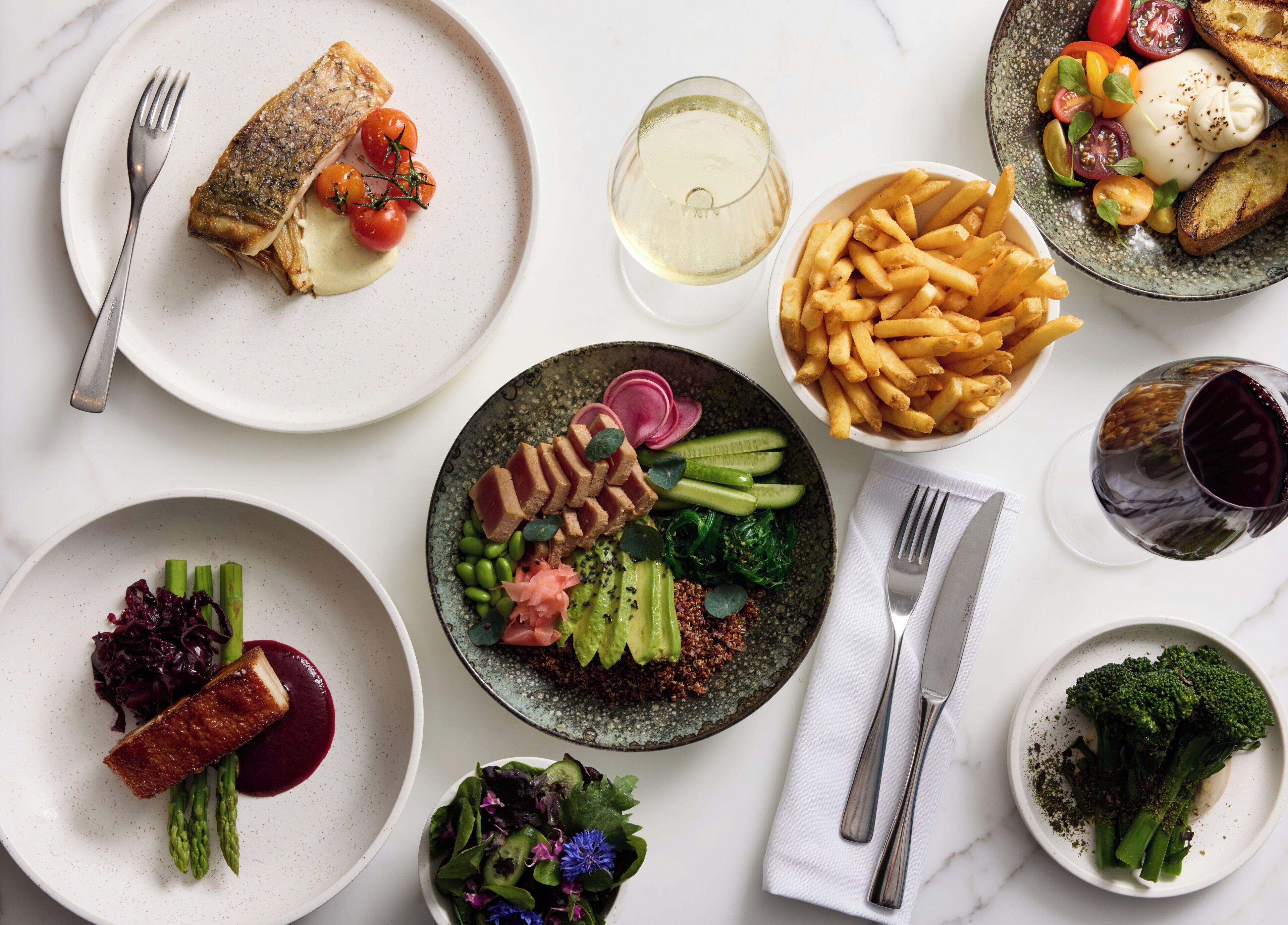 Diverse gerechten, waaronder vis, friet en groenten, op een eettafel.