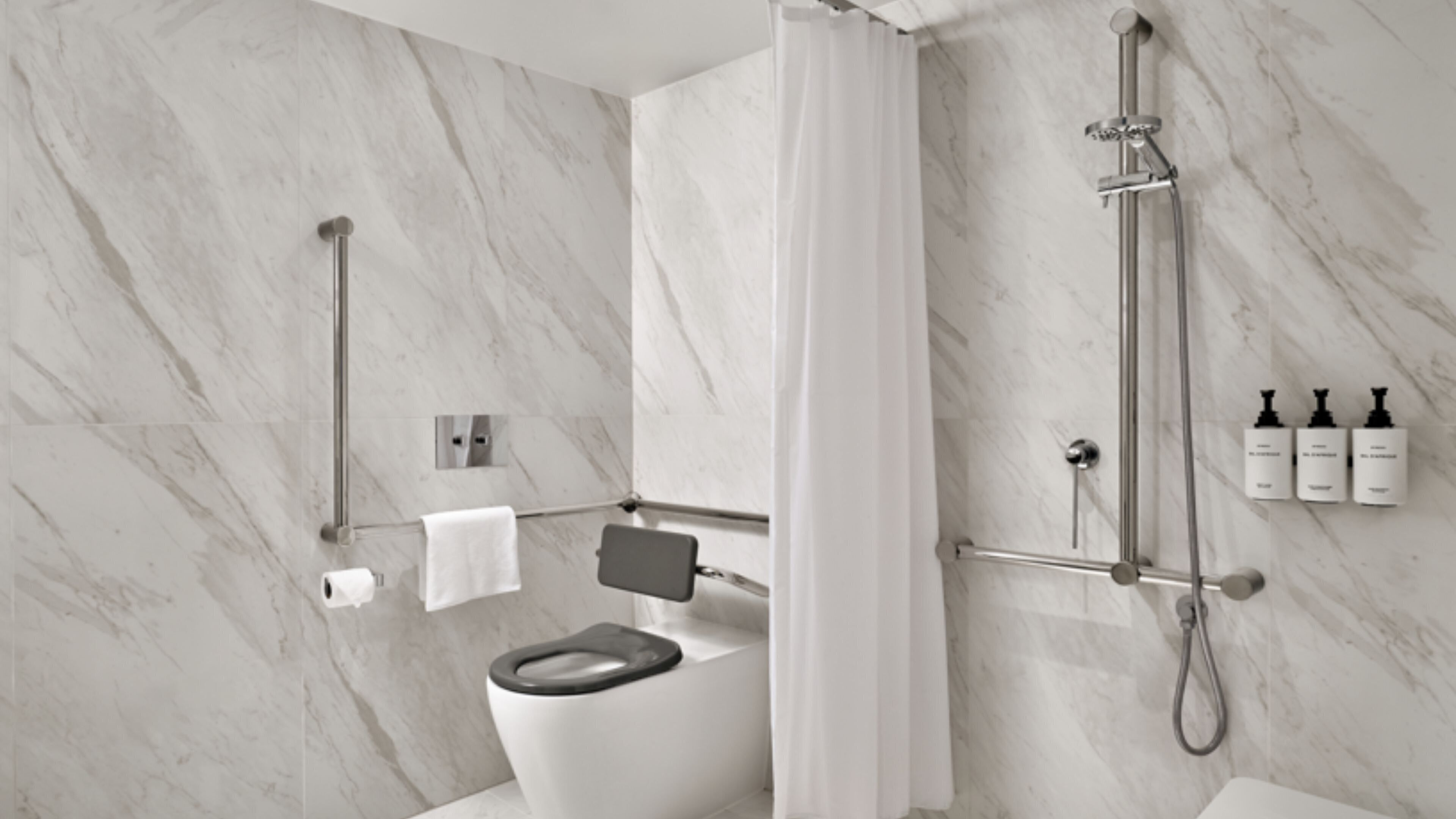 Un bagno moderno con WC, doccia e tre flaconi di articoli da toilette a parete.