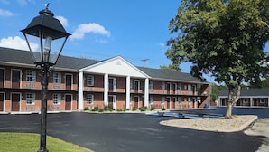 A multi-story hotel with a central courtyard, outdoor seating, and a lamp post. - Bourbon Capital Inn (Bardstown)