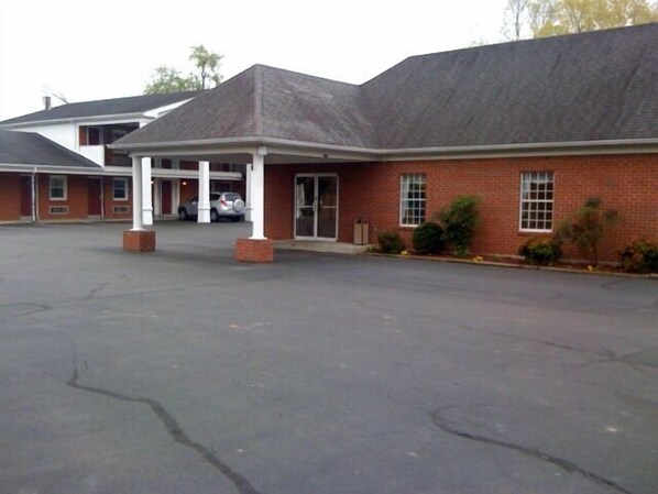 A building with a brick facade, a covered entrance, and a parking lot.