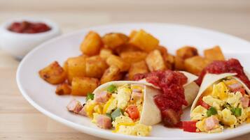 Une assiette contenant des tacos, des œufs brouillés et des pommes de terre rôties.