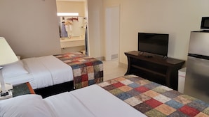 A hotel room with two beds, a TV, a refrigerator, and a bathroom visible through an open door. - Simple Rewards Inn (Hilton Head Island)