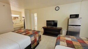 A hotel room with two beds, a TV, a refrigerator, and a clock on the wall. - Simple Rewards Inn (Hilton Head Island)