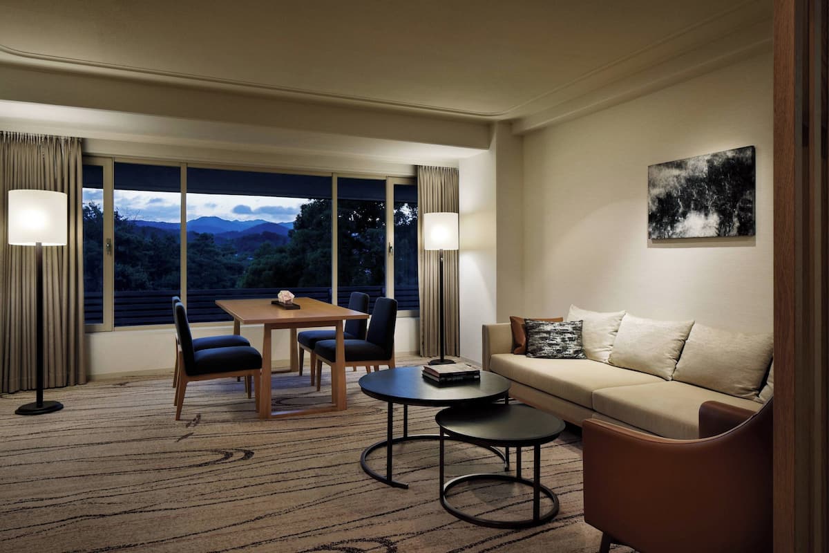 Ein Hotelzimmer mit Essbereich, einer Couch, einem Couchtisch und Bergblick durch große Fenster.