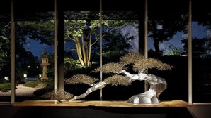 Eine Bonsai-Ausstellung mit traditioneller Steinlaterne und Holzboden.