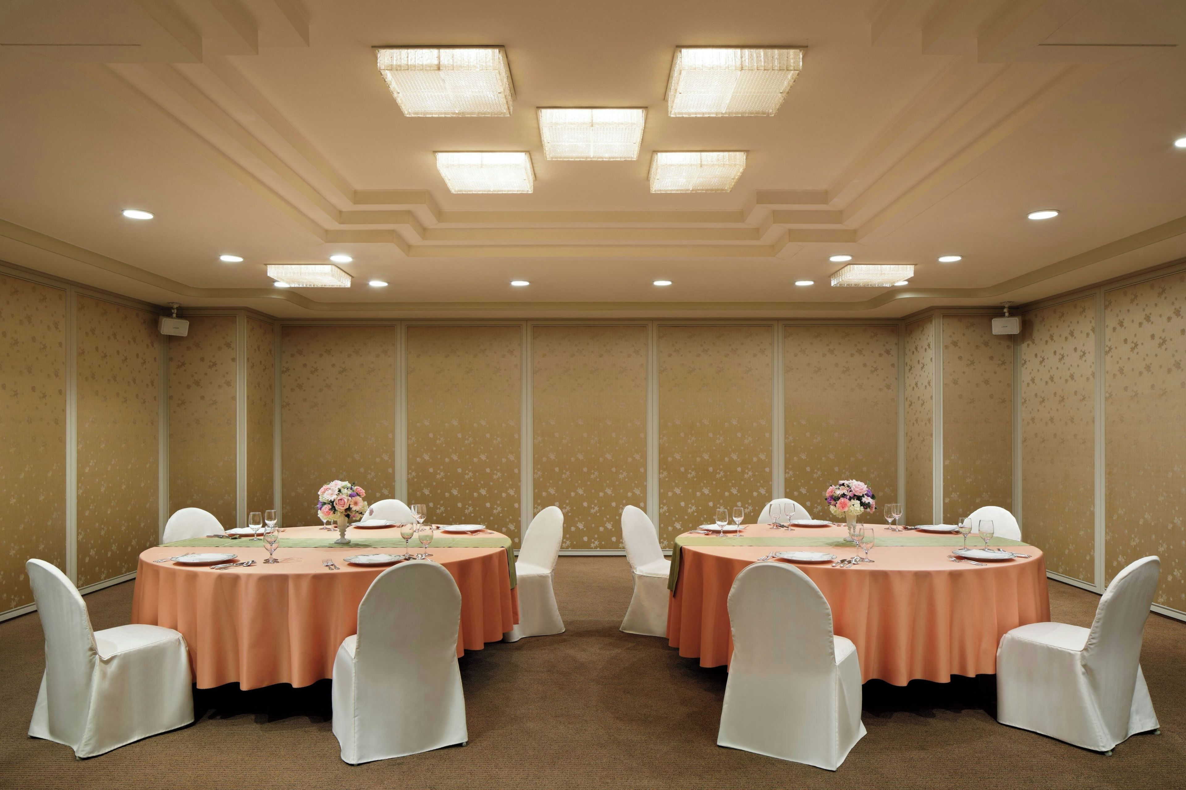 A conference room with round tables, white chairs, and floral centerpieces.