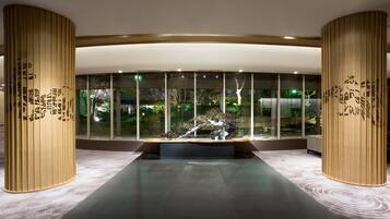 A modern lobby with a central seating area, large windows, and decorative wooden panels.