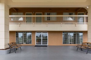 A building with a double-height balcony, large windows, and two benches.