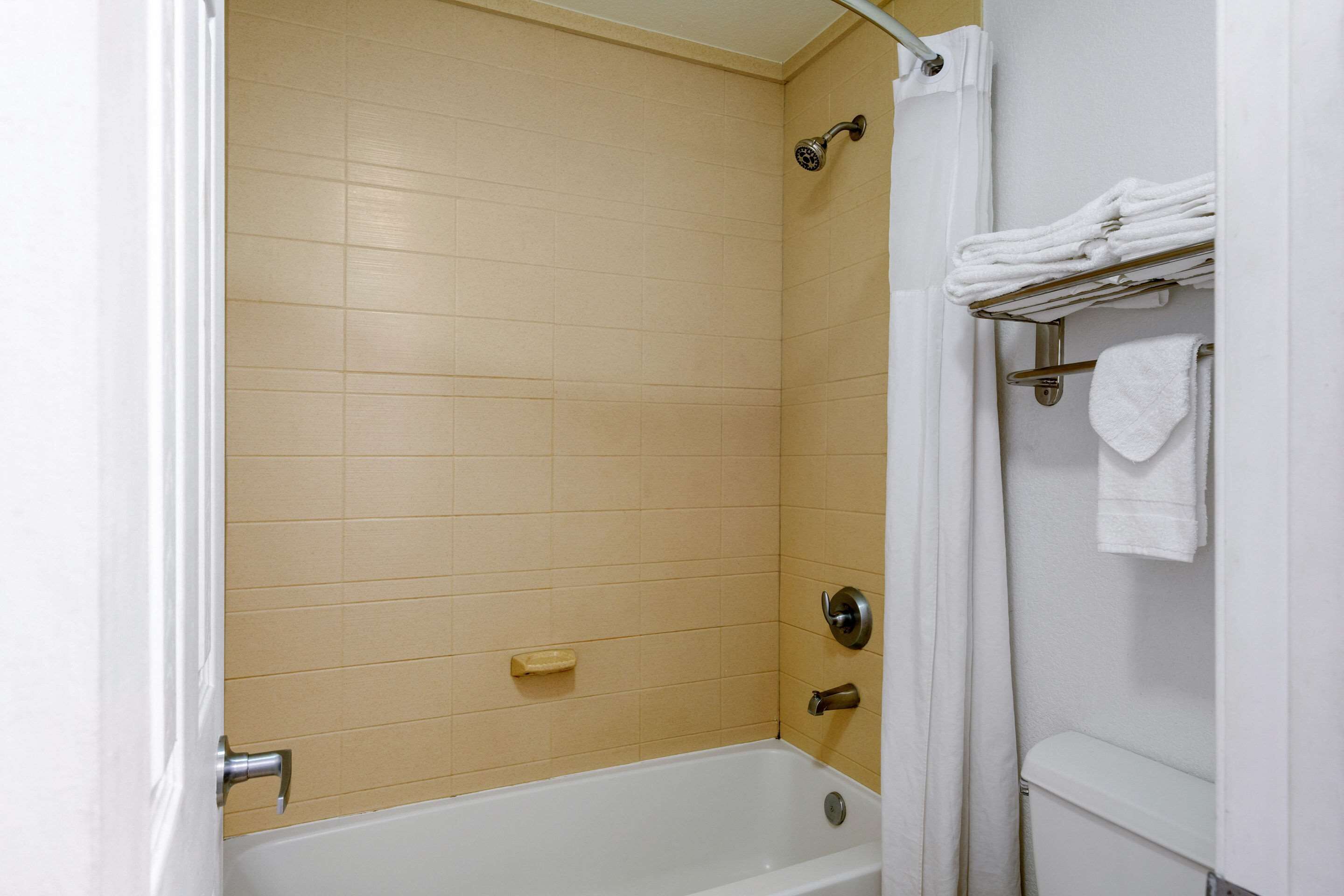 Un baño con bañera, ducha y retrete. Hay toallas en un tendedero.