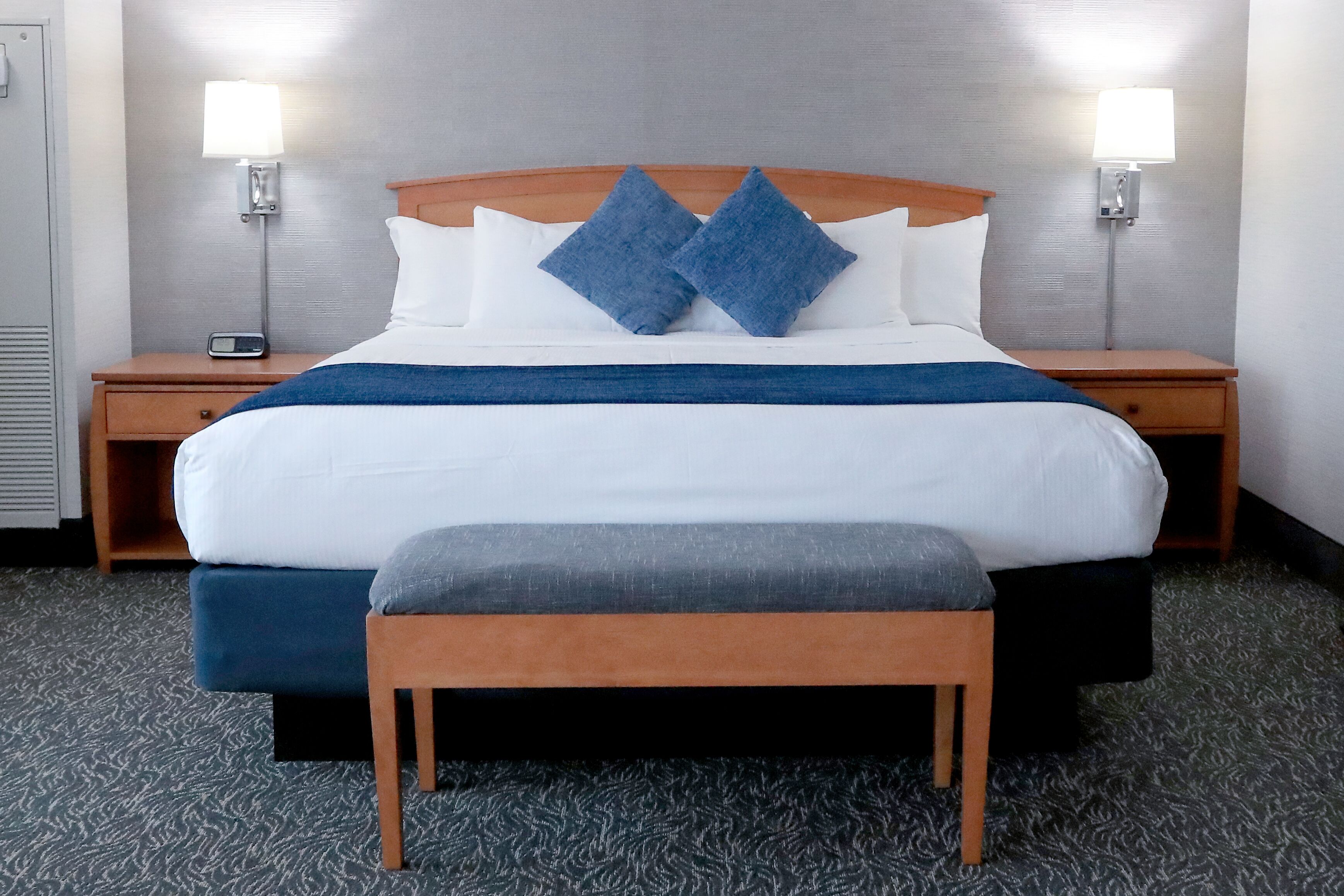 Camera d'albergo con un letto grande, due comodini, una panca e due lampade a parete.