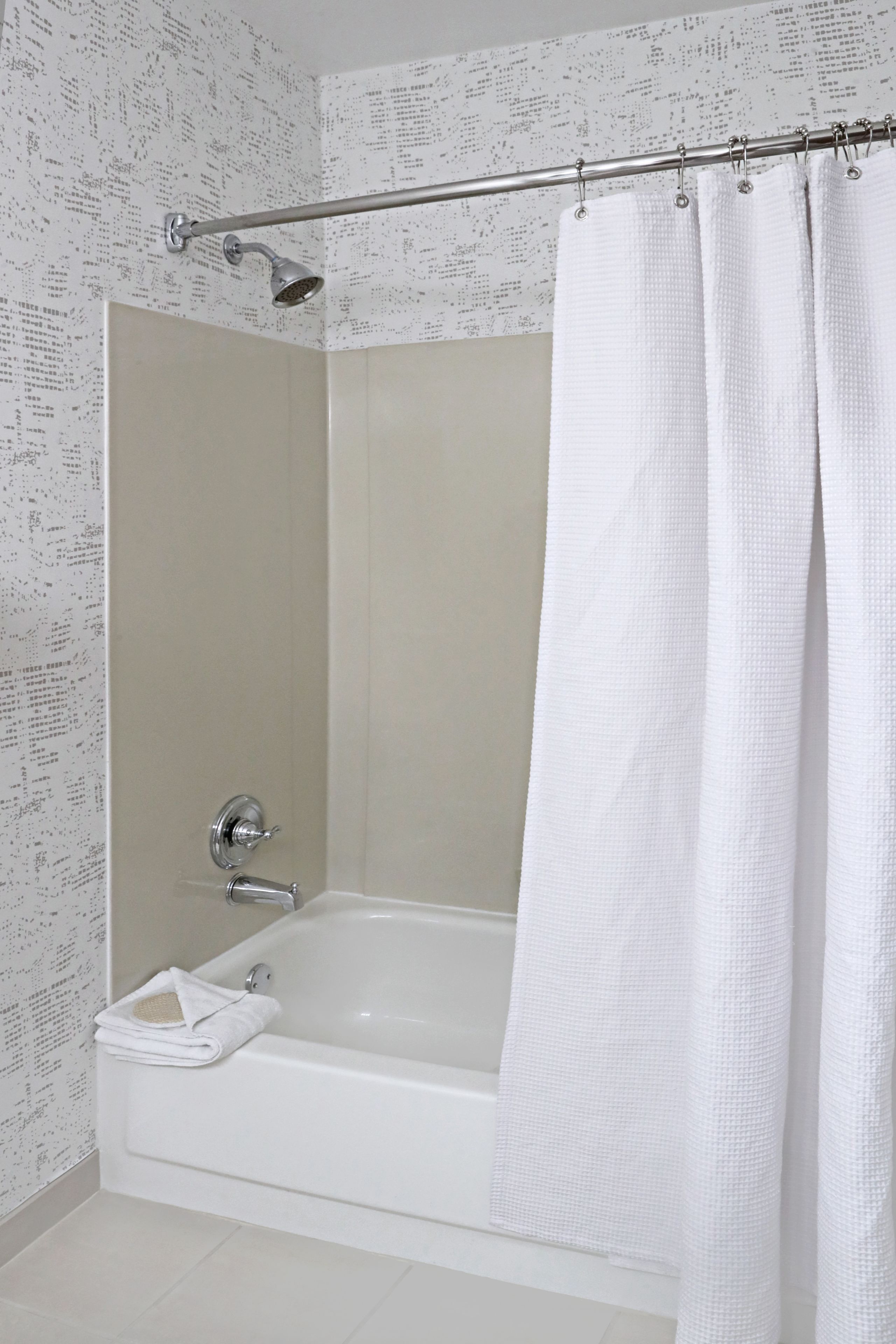 A modern bathroom with a bathtub, shower, and a curtain.