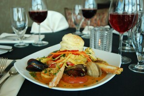 Savor a delicious seafood meal at this elegant dining table, complete with wine glasses and fine china.