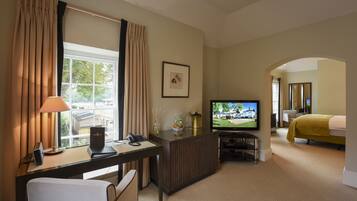 A hotel room with a desk, television, bed, and a view of a golf course.