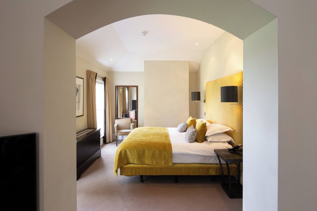 Een moderne hotelkamer met een bed, een bureau, een stoel en een televisie.