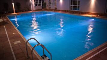 An indoor swimming pool with clear water, tiled edges, and a metal ladder.