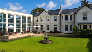 A large, white building with multiple windows and a central courtyard with a fountain. - Bedford Lodge Hotel & Spa (Newmarket)