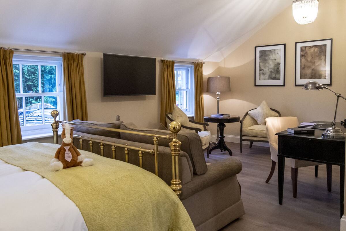 Een hotelkamer met een bed, een bank, een bureau, een stoel, een lamp en een televisie.