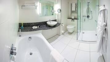 A modern bathroom with a bathtub, a sink, a toilet, and a glass-enclosed shower area.