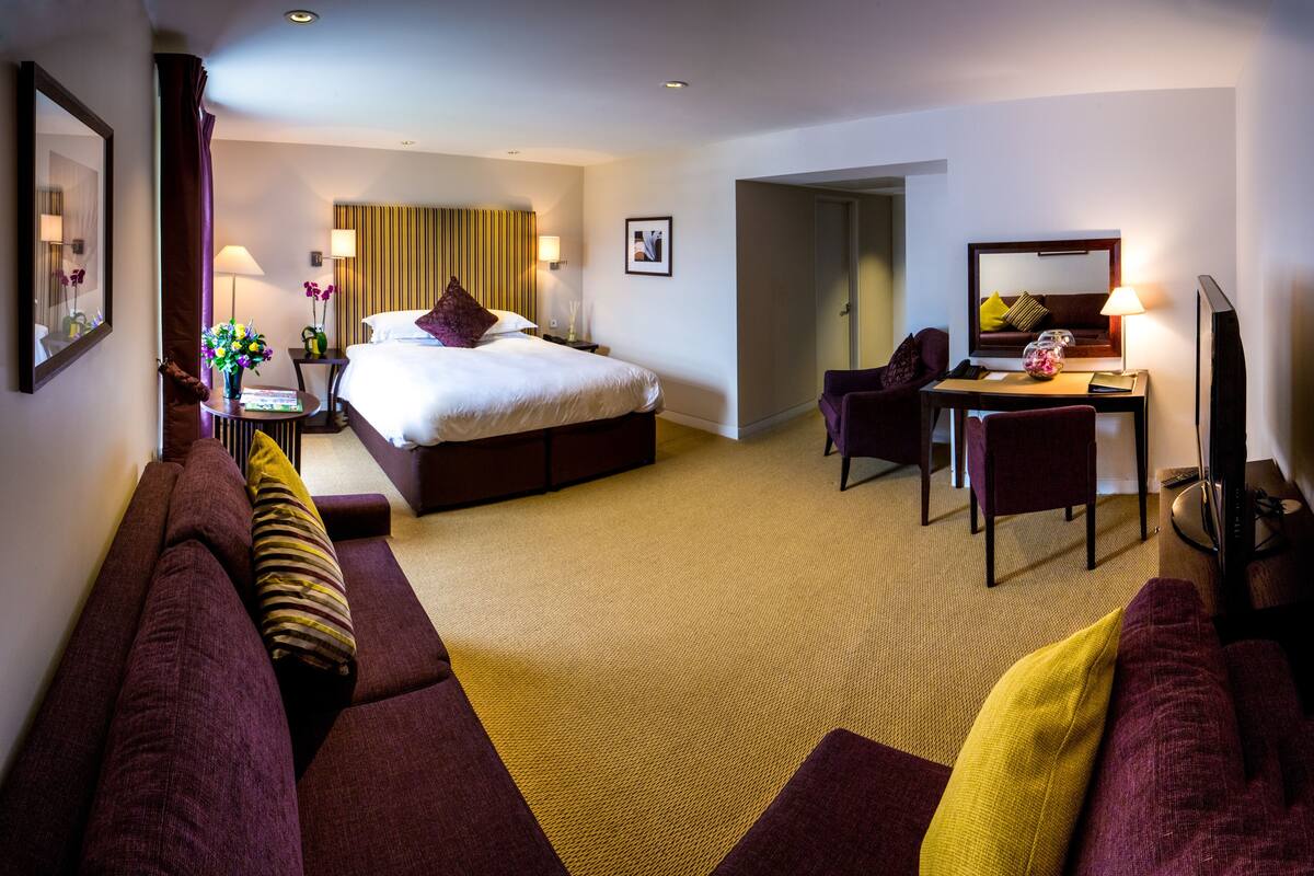 Een hotelkamer met een groot bed, een bureau, een stoel en een bank.