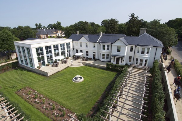 A large, white building with multiple windows and a central courtyard with a fountain.