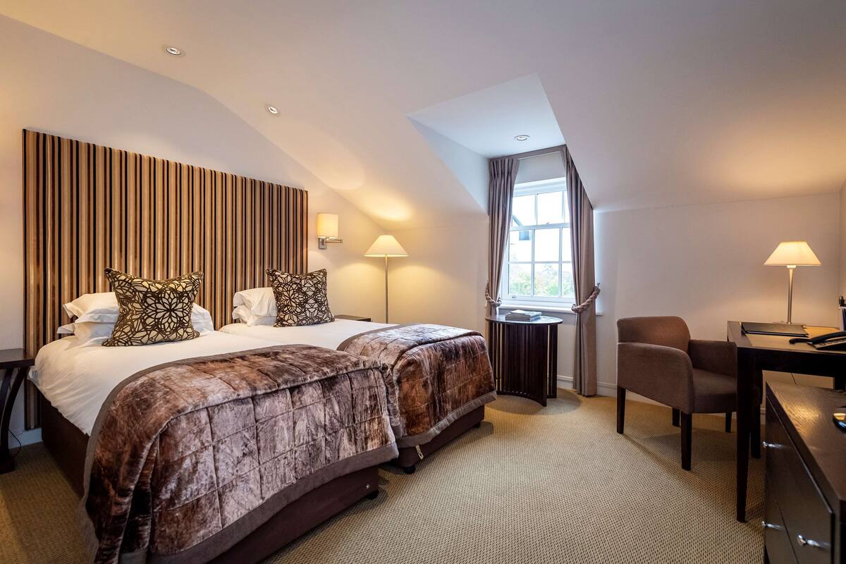 Een hotelkamer met een groot bed, twee nachtkastjes, een bureau en een stoel.