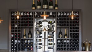 A wine cellar with a variety of wine bottles organized in racks and a selection of champagne bottles displayed on a shelf. - Bedford Lodge Hotel & Spa (Newmarket)