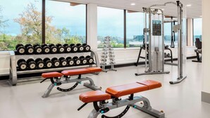 A gym with weightlifting equipment, benches, and dumbbells.