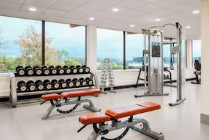 A gym with weightlifting equipment, benches, and dumbbells.