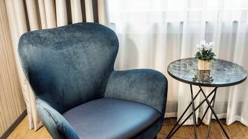 Un sillón azul y una mesita redonda con un florero.