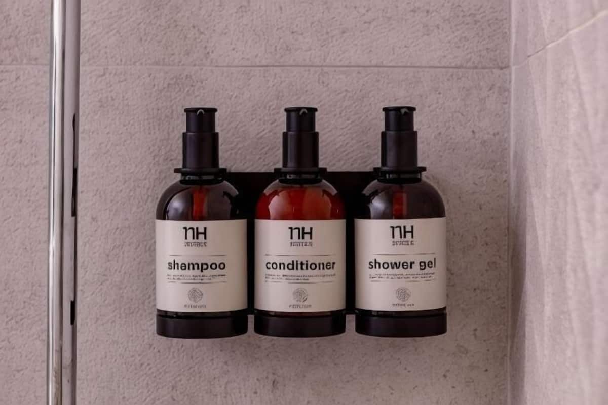 Drei Flaschen Shampoo, Conditioner und Duschgel an einer Wand.