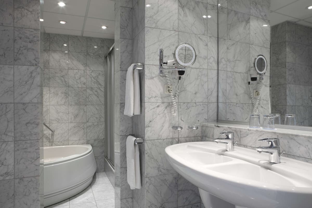 junior suite | bathroom | deep-soaking bathtub, rainfall showerhead, eco-friendly toiletries