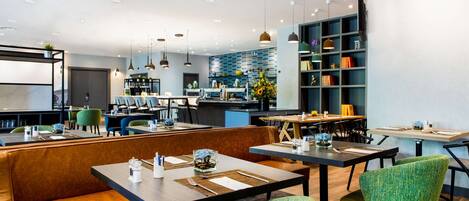Un restaurante moderno con barra, diferentes disposiciones de mesas y una cocina al fondo.