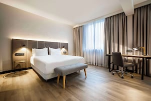 Una habitación de hotel moderna con una cama grande, mesitas de noche, un escritorio y una silla.