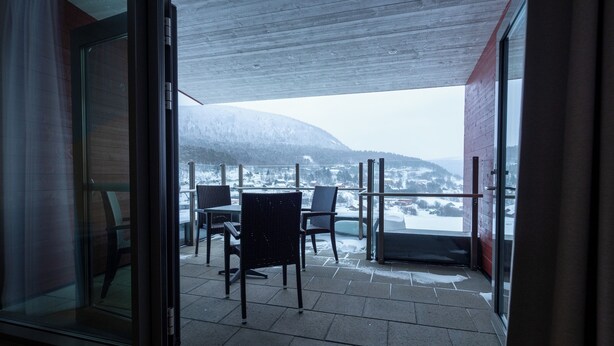 Ein Balkon mit Blick auf eine verschneite Landschaft und einen Berg.