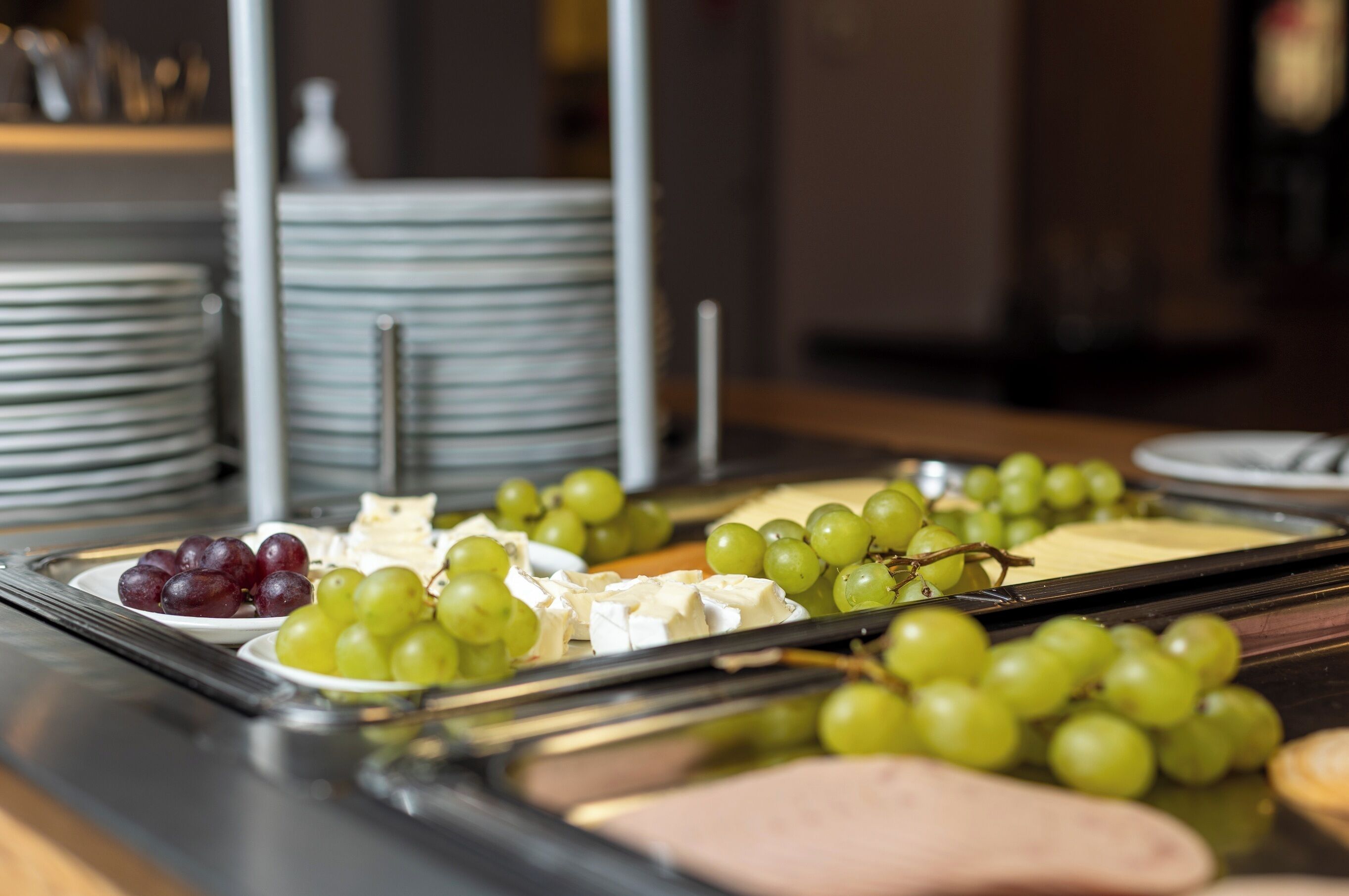Una mesa de buffet con platos de queso y uvas.