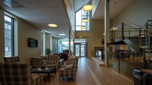 Eine geräumige Lobby mit hoher Decke, großen Fenstern und einer Treppe.
