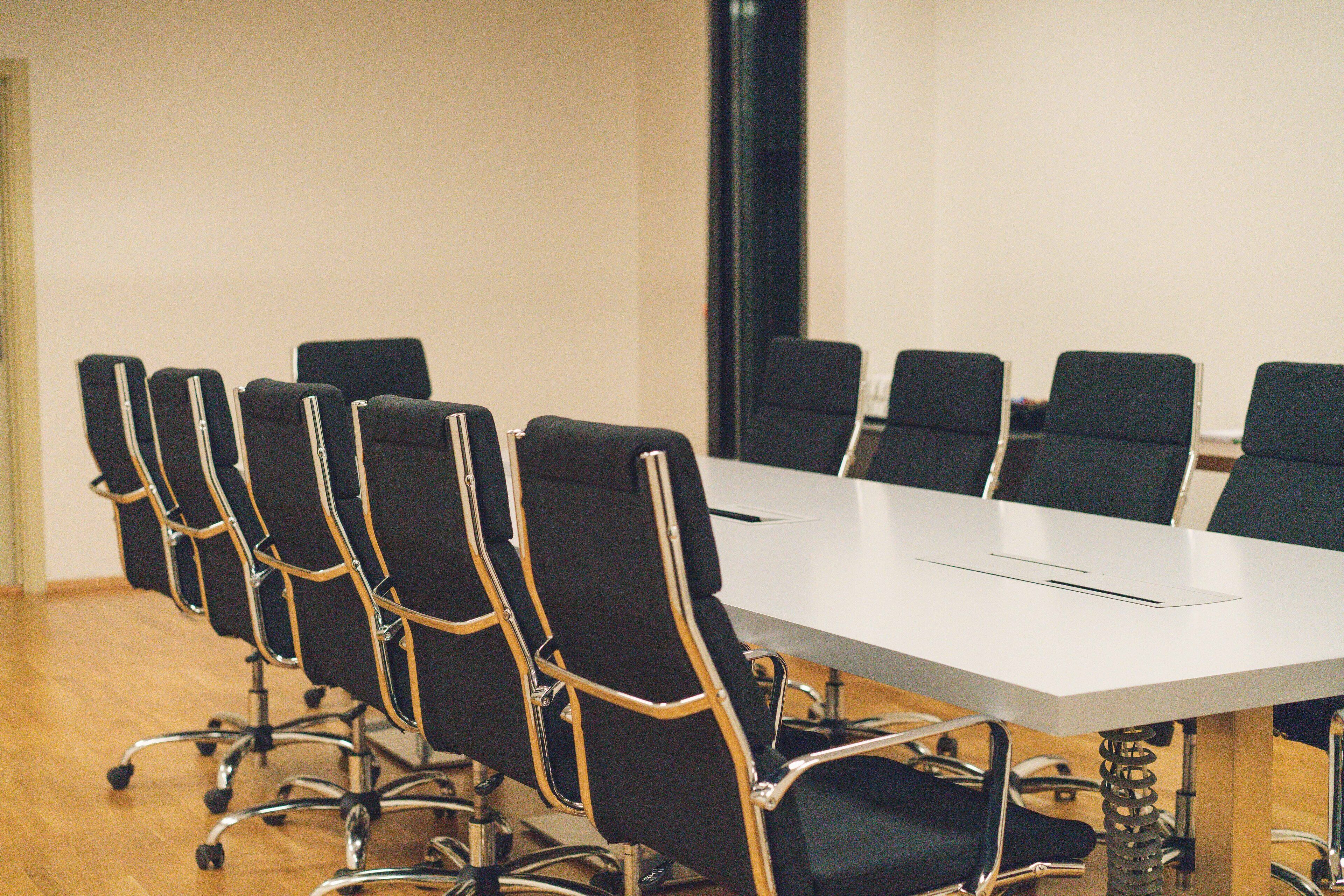A conference room with a long table and black chairs with metal frames.