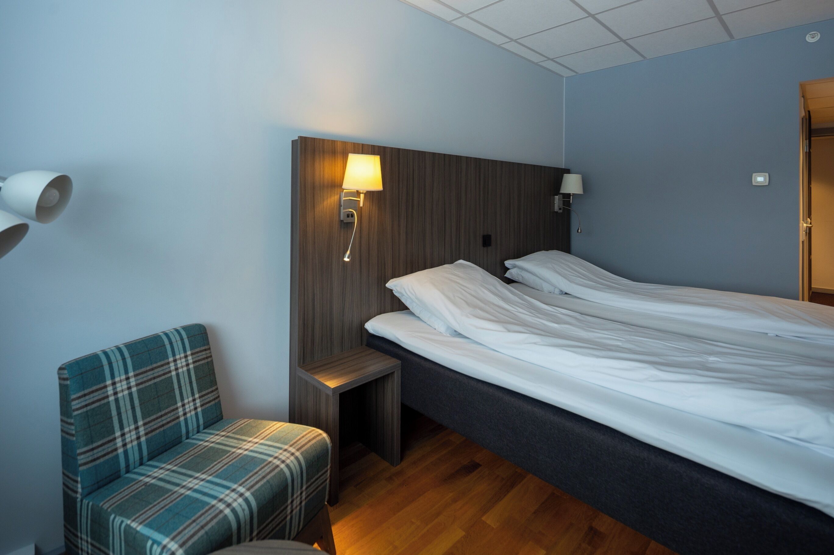 Une chambre d’hôtel avec un lit, un petit coin salon et une table de chevet.