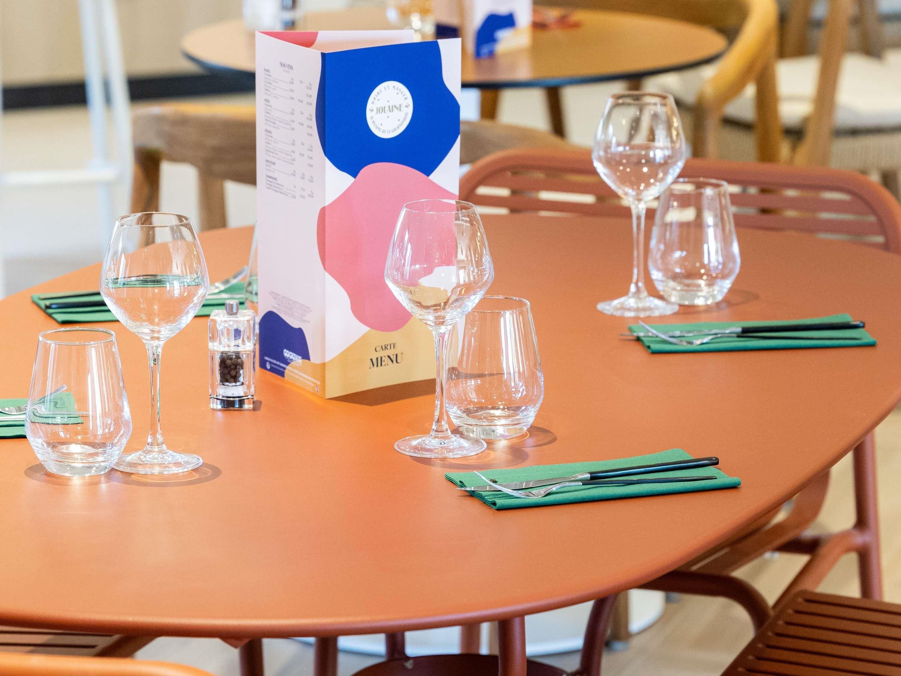 A table with empty wine glasses, a menu box, and green napkins.