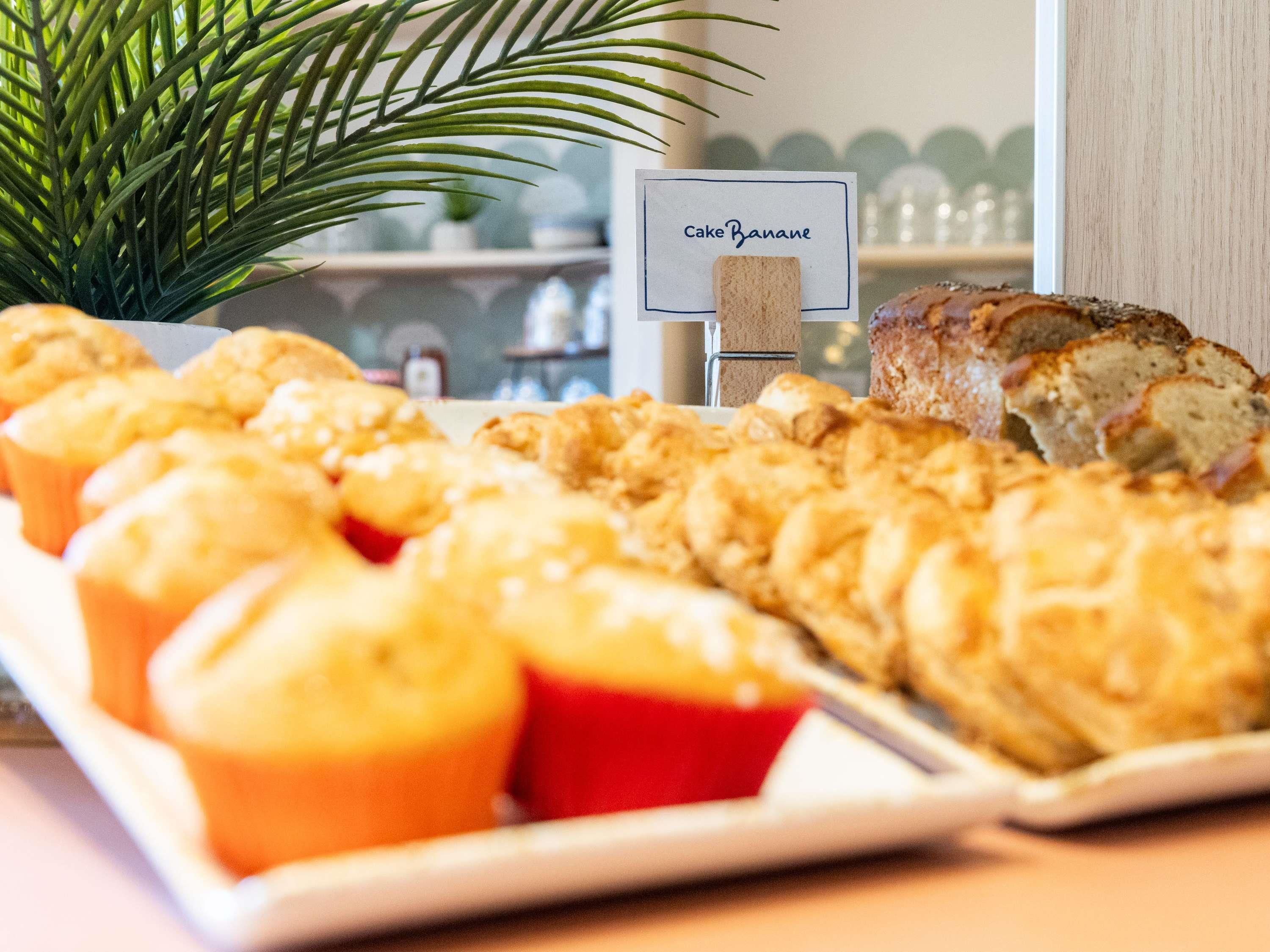 Una bandeja de pasteles y pan, con un letrero que dice 'Cake Banane' al fondo.