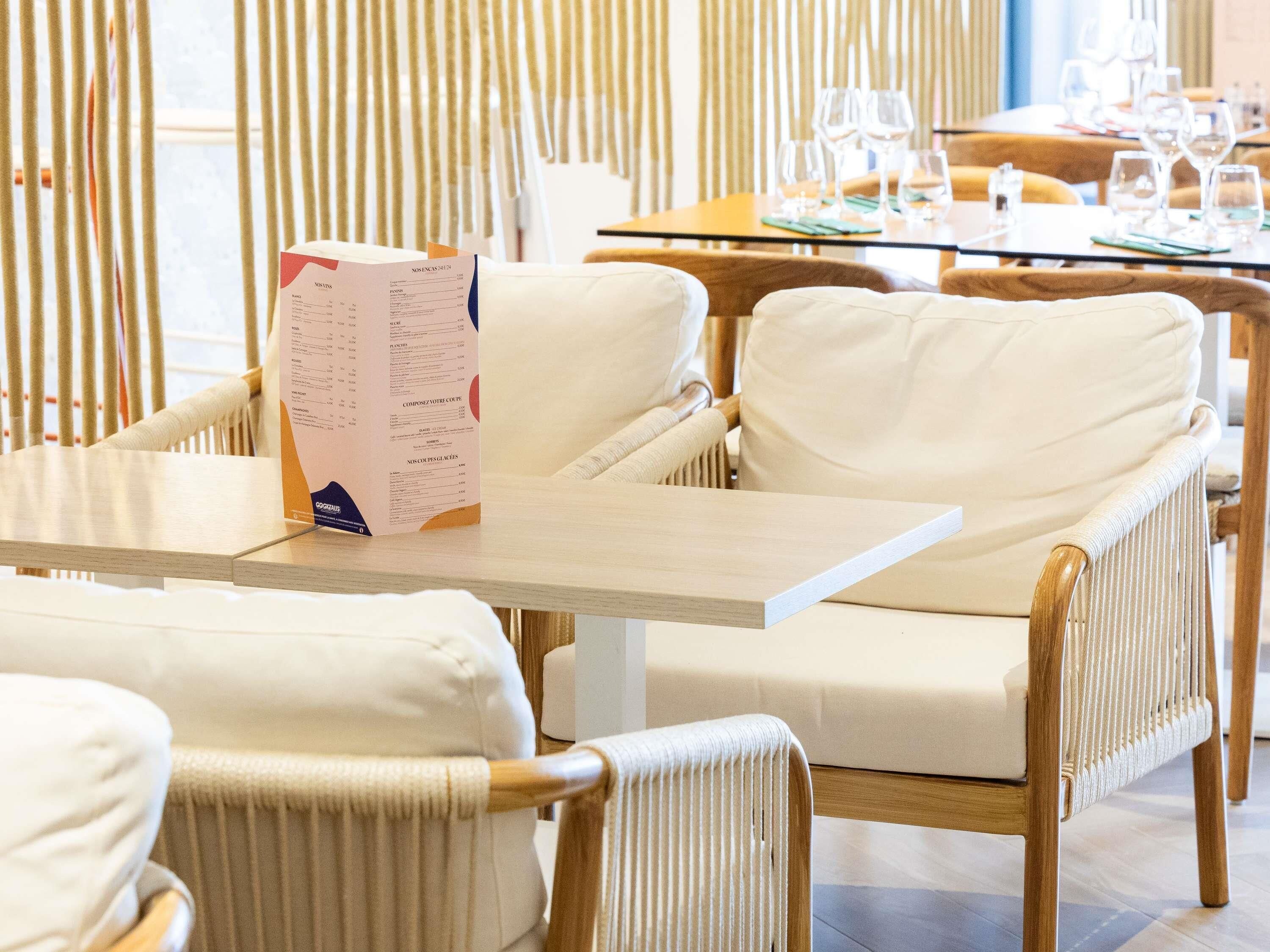 Ein Restaurantinneres mit Korbstühlen, einem Holztisch und einer Speisekarte auf dem Tisch.