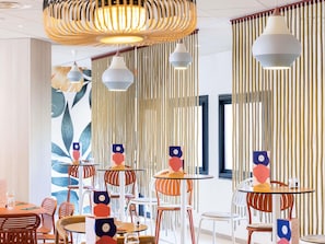 Un comedor moderno con mesas redondas, sillas color naranja y listones verticales de madera.