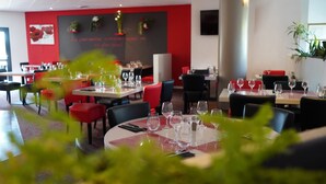 A restaurant with tables set for dining, chairs, and a wall with decorations. - Hôtel ibis Beziers Est Mediterranee (Villeneuve-les-Beziers)