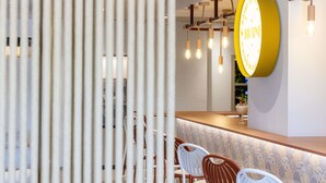 L’intérieur d’un restaurant avec un coin bar, des chaises blanches et un panneau jaune sur le mur.
