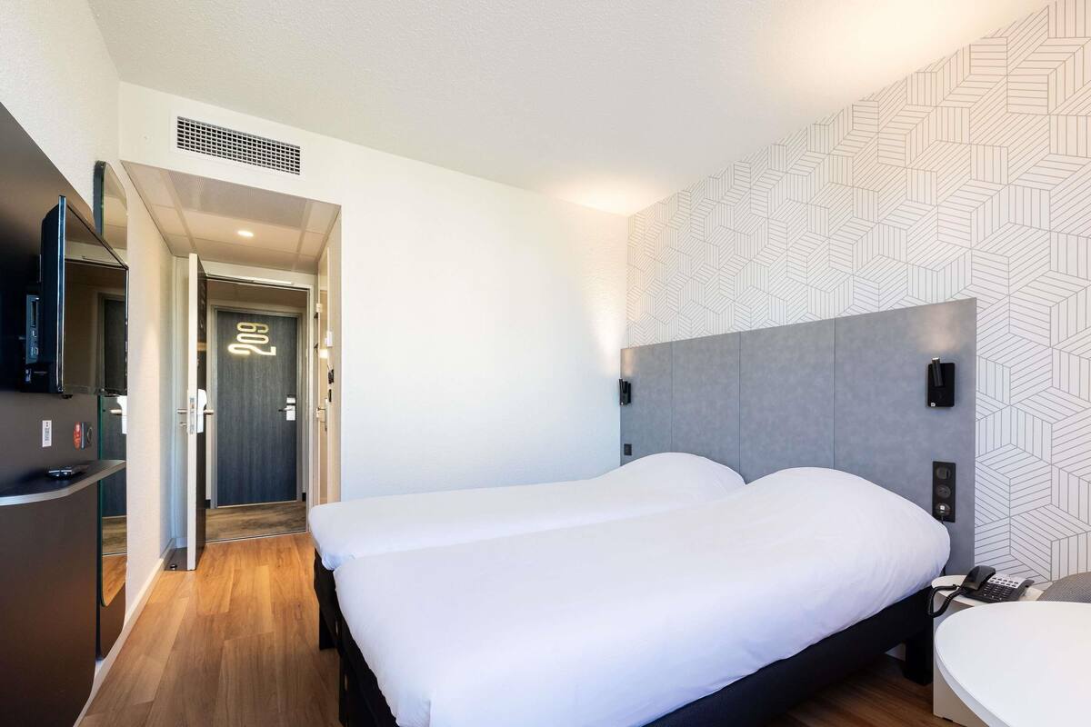 Ein Hotelzimmer mit einem groĂen Bett, einem Schreibtisch, einem Telefon und einem Fernseher.