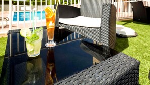 Une table en verre avec des boissons et une chaise en osier.