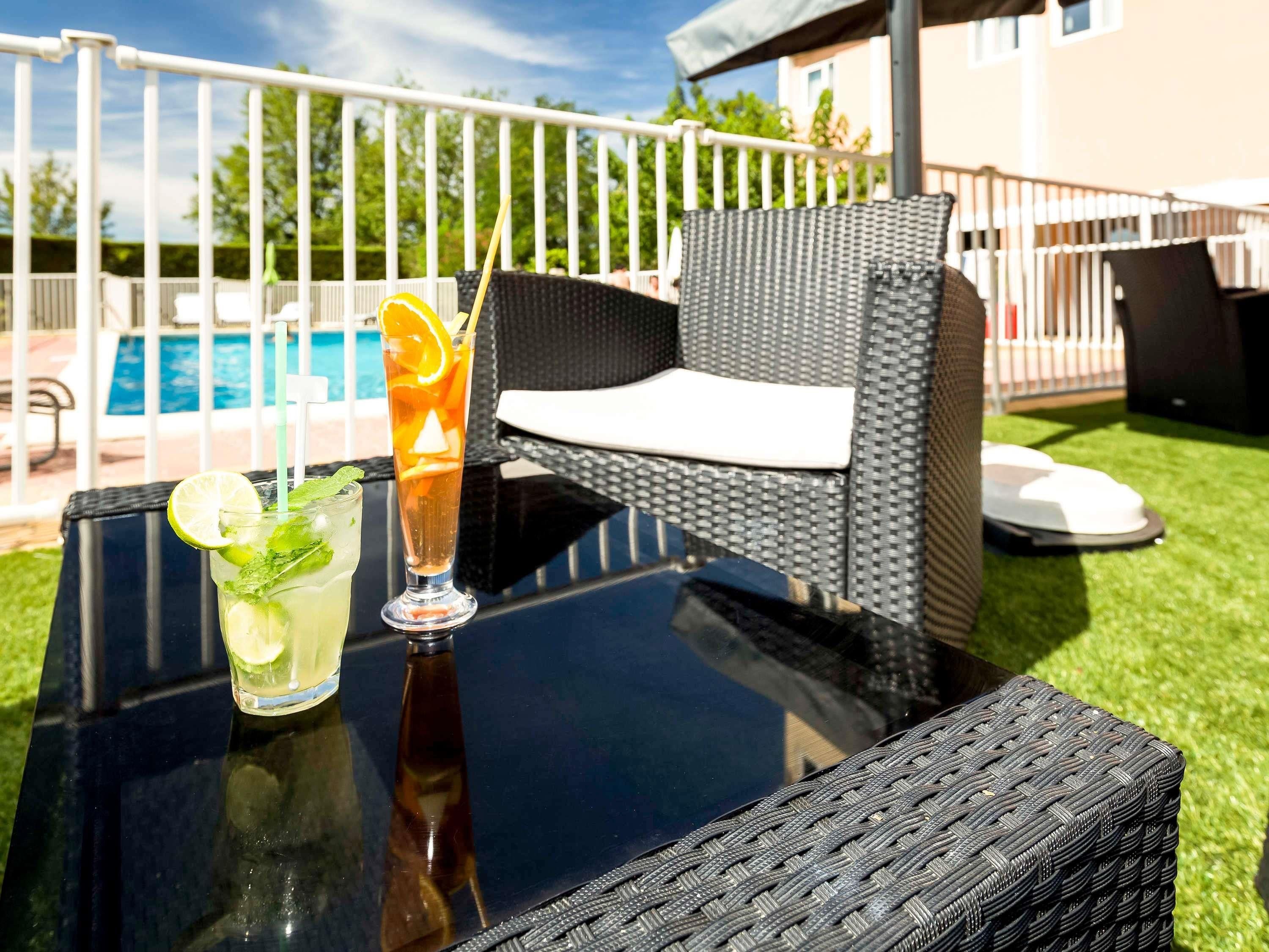 Une table en verre avec des boissons et une chaise en osier.