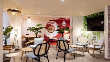 A modern interior with seating areas, a wall with a 'MUSIC' sign, and a television mounted on a green leafy wall.