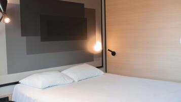Een moderne hotelkamer met een groot bed, een nachtkastje en een wandlamp.