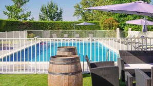 Une piscine agrémentée d’un tonneau en bois, de meubles en osier et de parasols.